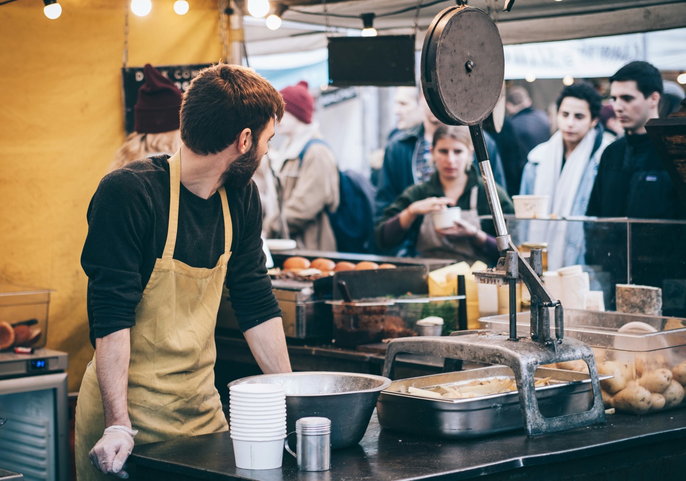A vendor preparing food for customers at a market stall